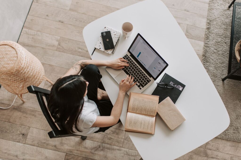 Estudante a estudar com portátil, cadernos e livros